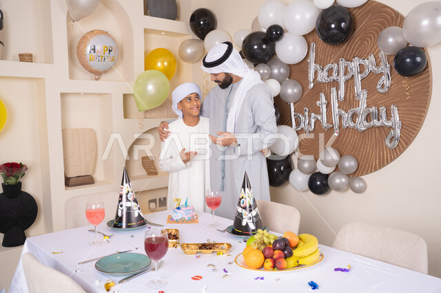 مفهوم الإهداء والتقدير،  ايماءات السعادة و السرور ، أعياد ومناسبات عائلية سعيدة، اب عربي خليجي اماراتي يقوم بالاحتفال بابنه ، عائلة عربية خليجية اماراتيه تقضي اوقات ممتعه ، زينة أعياد الميلاد