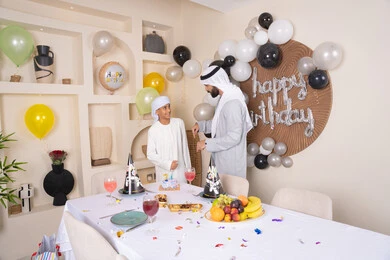 أعياد ومناسبات عائلية سعيدة، اب عربي خليجي اماراتي يقوم بالاحتفال بابنه ، الاستمتاع و الترفيه مع افراد الاسره ،مفهوم الإهداء والتقدير، عائلة عربية خليجية اماراتيه تقضي اوقات ممتعه ، زينة أعياد الميلاد ، ايماءات السعادة و السرور