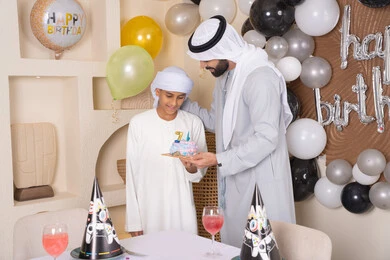 ايماءات السعادة و السرور ،مفهوم الإهداء والتقدير، أعياد ومناسبات عائلية سعيدة، اب عربي خليجي اماراتي يقوم بالاحتفال بابنه ، عائلة عربية خليجية اماراتيه تقضي اوقات ممتعه ، زينة أعياد الميلاد