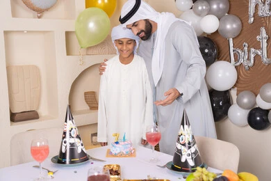 اب عربي خليجي اماراتي يقوم بالاحتفال بابنه ، الاستمتاع و الترفيه مع افراد الاسره ،مفهوم الإهداء والتقدير،  أعياد ومناسبات عائلية سعيدة، عائلة عربية خليجية اماراتيه تقضي اوقات ممتعه ، زينة أعياد الميلاد ، ايماءات السعادة و السرور