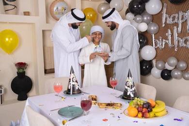 الاستمتاع و الترفيه مع افراد الاسره ،أعياد ومناسبات عائلية سعيدة، عائله عربيه خليجيه اماراتية تقوم بالاحتفال ، زينة أعياد الميلاد ، مفهوم الإهداء والتقدير، ايماءات السعادة و السرور