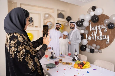 امراه تقوم بالتقاط صورة تذكارية من خلال الجوال ، عائله عربيه خليجيه اماراتية تقوم بالاحتفال بعيد الميلاد ، توثيق اللحظات السعيدة، قضاء أوقات ممتعه و الاحتفال بالمناسبات العائلية، زينة أعياد الميلاد و المناسبات، ايماءات السعادة و السرور