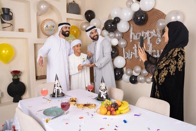 Documenting happy moments, having fun and celebrating family occasions, birthday and event decorations, an Arab Gulf Emirati family celebrating a birthday, a woman taking a souvenir photo with her mobile phone, gestures of happiness and pleasure