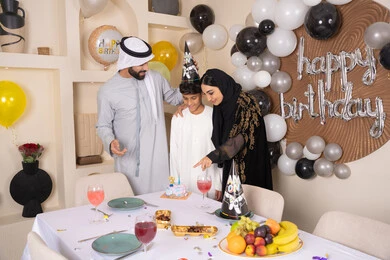 أجواء أسرية مليئة بالألفة، بلالين وكعكة يوم الميلاد المزينة بالشموع، مشاركة وتقديم الهدايا بالمناسبات وأعياد الميلاد ، إيماءات الفرح و السعادة، مشاعر الحب والحنان في اجتماع عائلي سعيد، عائلة عربية خليجية إماراتية تقضي أوقات ممتعه في المنزل