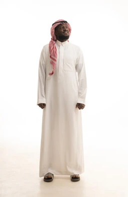الاهتمام بالمظهر الخارجي، الشعور بالثقة في النفس، الوقوف باستقامة واعتدال, بورتريه لرجل عربي خليجي سعودي يرتدي الثوب التقليدي ينظر الى شيء ما بتعابير السعادة والسرور, صورة الجسم بالطول الكامل, خلفية بيضاء