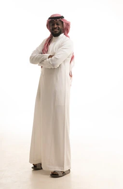 الوقوف بثقة بإيماءات التحديق والنظر إلى الكاميرا، بورتريه لرجل عربي خليجي سعودي يرتدي الشماغ والثوب السعودي التقليدي يقف بإيدي متقاطعه، الاهتمام بالمظهر الخارجي، الجسم بالطول الكامل، خلفية بيضاء