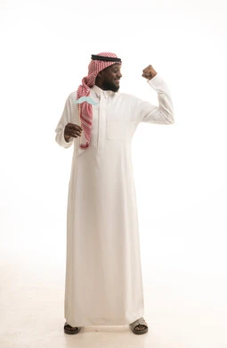 تعزيز الصحة الجسدية للذكور، الإحتفال بالمناسبات العالمية، المحافظة على اللياقة والقوة العضلية، اليوم العالمي للرجل 19 نوفمبر، بورتريه لرجل عربي خليجي سعودي يرتدي الثوب التقليدي والشماغ يمسك بيدية قصاصة ورقية على شكل شارب، الطول الكامل للجسم، خلفية بيضاء