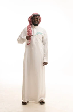 إيماءات الثقة والاعتزاز بالنفس، الاهتمام بالصحة الجسدية للذكور، مفهوم القوة والرجولة، بورتريه لرجل عربي خليجي سعودي يرتدي الثوب التقليدي والشماغ يضع في جيبه قصاصة ورقية على شكل شارب ويقوم بالإشارة اليها، صورة لكامل الجسم، خلفية بيضاء