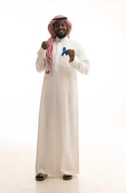 The feeling of strength and success, gestures of interaction and integration, a portrait of a young Arab Gulf Saudi man wearing traditional attire holding a blue ribbon for disease awareness, full-body, white background. The feeling of strength and success, gestures of interaction and integration, a portrait of a young Arab Gulf Saudi man wearing traditional attire holding a blue ribbon for disease awareness, full-body, white background.