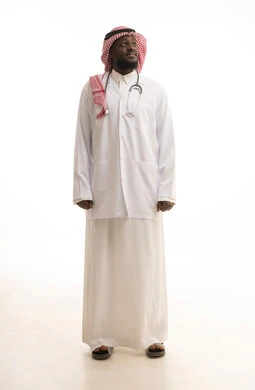 Looking at something, standing upright with gestures of self-confidence, working in the healthcare sector in Saudi Arabia, conducting medical examinations and providing treatment services to patients, a portrait of an Arab Gulf Saudi doctor wearing a coat and stethoscope looking at the camera, full-body, white background.