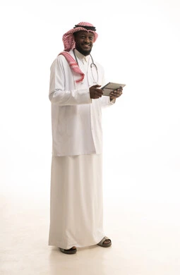 Description of the medical condition and providing medical consultations, monitoring the patient's electronic medical record, a portrait of a Saudi Gulf Arab doctor wearing a coat and stethoscope holding a tablet in his hand, description of treatment and medical and educational awareness, full-body image, white background.
