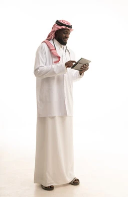 Monitoring the patient's electronic medical record, describing the medical condition and providing medical consultations, a portrait of an Arab Gulf Saudi doctor wearing a coat and stethoscope holding a tablet in his hand, describing treatment and medical and educational awareness, full body image, white background.