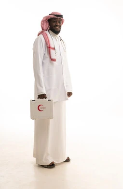 مبادئ التعامل مع حالات الطوارئ، الأدوات والمعدات الطبية اللازمة، تقديم الخدمات الصحية الطارئة للمرضى، بورتريه لطبيب عربي سعودي خليجي يرتدي الثوب التقليدي و المعطف الطبي يحمل بيده حقيبة الاسعافات الأولية، العمل في القطاع الصحي، الجسم بالطول الكامل، خلفية بيضاء