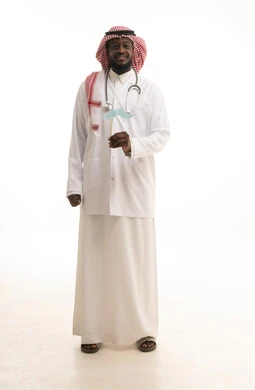ايماءات السعادة و السرور،  مفهوم الطب والرعاية الصحية، بورتريه لطبيب عربي خليجي سعودي يرتدي الشماغ والمعطف الطبي والسماعات الطبية يحمل بيده عود خشبي مع قصاصة ورقية على شكل شارب، الطول الكامل للجسم، خلفية بيضاء