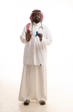 مفهوم العمل في القطاع الصحي، بورتريه  لطبيب عربي خليجي سعودي يرتدي الشماغ و المعطف الطبي يحمل شريط ازرق للتوعيه بسرطان البروستات، رفع الكف للتحذير من تجاهل الكشف عن المرض، ايماءات التوقف عن إهمال الصحه الجسديه، الجسم بالطول الكامل، خلفية بيضاء