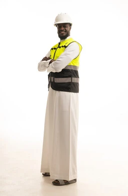 الوقوف بايدي متقاطعة بتعابير السعادة والسرور, مهن ووظائف سعودية, بورتريه لرجل عربي سعودي خليجي يرتدي الثوب والسترة ويضع خوذه الحماية, صورة الجسم بالطول الكامل, خلفية بيضاء