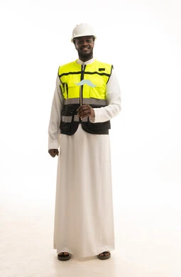 النظر الى الكاميرا بإيماءات الثقة والاعتزاز بالنفس، الاهتمام بالصحة الجسدية للذكور، مفهوم القوة والرجولة، بورتريه لمهندس عربي خليجي سعودي يرتدي الثوب التقليدي و الخوذة وسترة الحماية يمسك بيدية قصاصة ورقية على شكل شارب، صورة لكامل الجسم، خلفية بيضاء