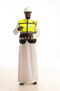 الاهتمام بالصحة الجسدية للذكور، النظر الى الكاميرا بإيماءات الثقة والاعتزاز بالنفس، مفهوم القوة والرجولة، بورتريه لمهندس عربي خليجي سعودي يرتدي الثوب التقليدي و الخوذة وسترة الحماية يمسك بيدية قصاصة ورقية على شكل شارب ويقوم بالإشارة اليها، صورة لكامل الجسم، خلفية بيضاء