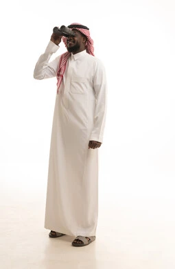 Love of exploration and adventure, seeing distant things through a telescope, gestures of enjoyment and pleasure, a portrait of an Arab Gulf Saudi man wearing traditional attire and a ghutrah holding a binocular in his hand looking at something, full-body image, white background.