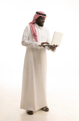 Making a video call using a laptop, a portrait of a Saudi Arabian Gulf man wearing traditional attire and a ghutrah browsing the internet, using modern technology devices, remote work, holding a business meeting via laptop, full-body, white background. Making a video call using a laptop, a portrait of a Saudi Arabian Gulf man wearing traditional attire and a ghutrah browsing the internet, using modern technology devices, remote work, holding a business meeting via laptop, full-body, white background.