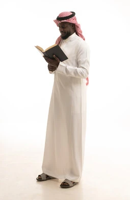 قضاء وقت الفراغ بالتعلم والثقافة،  هواية حب المطالعة و الاستكشاف، مفهوم محو الامية، بورتريه لرجل عربي خليجي سعودي يرتدي الثوب التقليدي والشماغ يحمل بيده كتاب علمي تثقيفي، الجسم بالطول الكامل، خلفية بيضاء