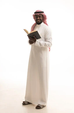 هواية حب المطالعة و الاستكشاف، مفهوم محو الامية, قضاء وقت الفراغ بالتعلم والثقافة، بورتريه لرجل عربي خليجي سعودي يرتدي الثوب التقليدي والشماغ يحمل بيده كتاب علمي تثقيفي، الجسم بالطول الكامل، خلفية بيضاء