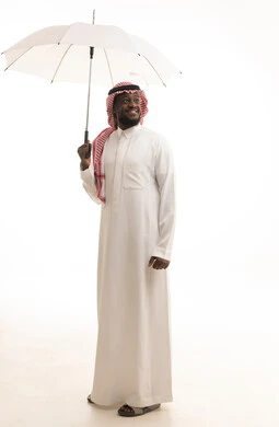 التظلل من أشعة الشمس، النظر إلى شيء ما بإيماءات السعادة والسرور, الحماية من الأمطار في الشتاء، بورتريه لرجل عربي سعودي يرتدي الزي التقليدي و الشماغ  بيده مظلة بيضاء, الجسم بالطول الكامل, خلفية بيضاء