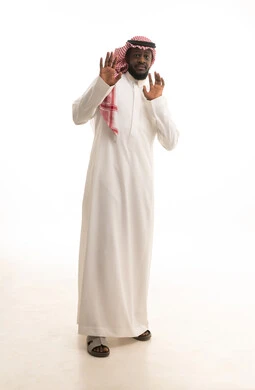 Anxiety, caution, and keeping away from something, protecting oneself from external harm, a portrait of a Saudi Arabian Gulf man wearing traditional attire and a ghutrah, raising his hands upwards in gestures of stop and do not approach, the concept of caution and maintaining distance, full-body, white background.