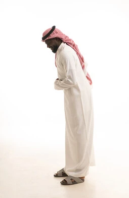 بورتريه لرجل عربي خليجي سعودي اسمر يرتدي الثوب الأبيض و الشماغ  يضع يده على بطنه بتعابير الضحك الهستيري، ايماءات البهجة والسرور الشديد، الشعور بالفرح والسعادة، الجسم بالطول الكامل، خلفية بيضاء