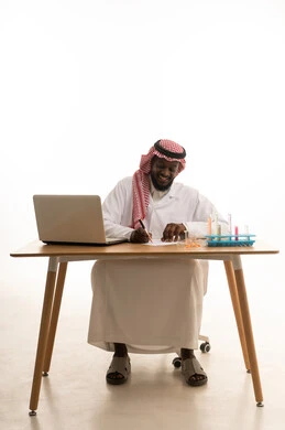 تدوين النتائج والملاحظات الهامة، الجلوس في معمل الكيمياء، بورتريه لطبيب عربي خليجي سعودي يرتدي المعطف الطبي الابيض و الشماغ يجلس خلف الطاولة امام الحاسب المحمول , استخدام انابيب الاختبار لاجراء التجارب في المختبر ، التفاعلات الكيميائية  ، مفهوم الكيمياء الحيوية، خلفية بيضاء