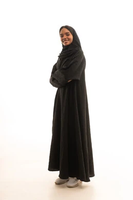 Expressions of joy and happiness, the concept of softness and femininity, attention to elegance and appearance, a portrait of a Gulf Arab Saudi girl wearing a hijab and abaya looking with gestures of self-confidence, white background.