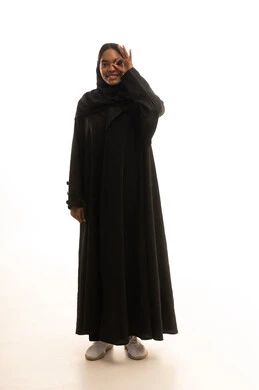 Expressions of agreement and acceptance, looking at the camera with gestures of joy, expressions of admiration and satisfaction, a portrait of a Gulf Arab Saudi girl wearing a hijab and abaya, raising her hand upwards with a sign of excellence and quality, white background.