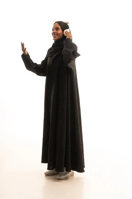The concept of listening and hearing, spending enjoyable time on the weekend, using headphone technology, a portrait of an Arab Gulf Saudi university student wearing an abaya and hijab, wearing headphones, listening to music with expressions of happiness and joy, white background.