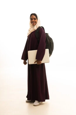 Using a laptop, research and scientific studies, a portrait of a Saudi Arabian Gulf Arab university student with dark skin wearing an abaya and hijab and carrying a backpack using a laptop, advanced academic universities in Saudi Arabia.