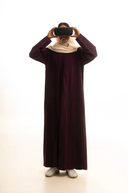 The use of technology and modern techniques, expressions of integration and focus, setting a specific goal, a portrait of a Gulf Arab Saudi woman wearing an abaya and hijab, wearing VR glasses, with a white background.