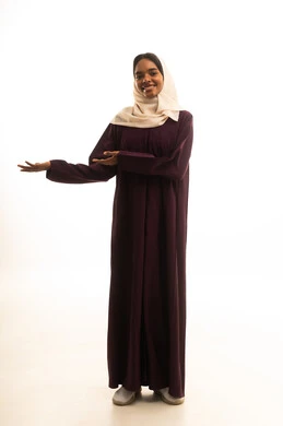 إشارات وحركات يدين تدل على هذا المكان (هنا)، تحديد موقع معين ، بورتريه لامرأة عربية خليجية سعودية مبتسمة ترتدي الحجاب والعباءة ترفع إصبعها السبابة تشير إلى شيء ما،الجسم بالطول الكامل، خلفية بيضاء