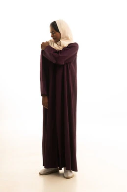 طلب المساعده والحاجه للعلاج، الأوجاع والآلام العصبية والعضلية، التهاب العضلات والمفاصل، بورتريه  لفتاة عربيه خليجية سعودية ترتدي الحجاب والعباءة تضع يدها على كتفها بايماءات الألم والتعب والأرهاق، حالة اسعافية طارئة، صورة الجسم الطول الكامل, خلفية بيضاء