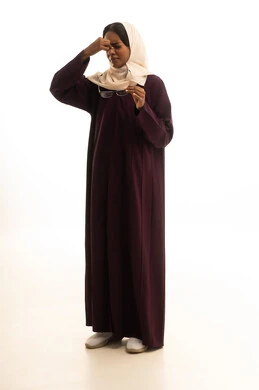 الصداع وألم الرأس، المعاناة من آلام الشقيقة، الحاجة للهدوء والراحة، إمرأة عربية خليجية سعودية ترتدي العباءة والحجاب تضع يديها على رأسها بايماءات التعب والارهاق، خلفية بيضاء