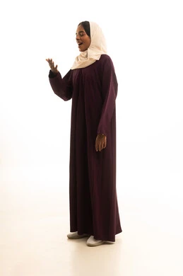 ايماءات الدهشة والاستغراب، بورتريه لإمرأة عربية خليجية سعودية ترتدي العباءة والحجاب تنظر إلى يدها بفرح وسعادة، صورة لكامل الجسم، خلفية بيضاء