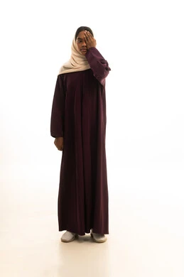 صحة العيون وفحوصات النظر الدورية، بورتريه لامرأة عربية خليجية سعودية ترتدي العباءة والحجاب تشير بعلامة تدل على اختبار الرؤية، الجسم بالطول الكامل، خلفية بيضاء