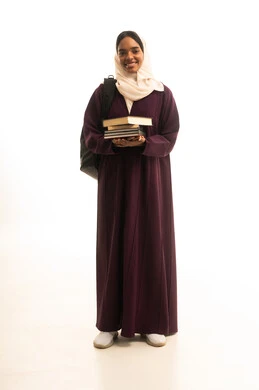 ايماءات السرور والسعادة، التعليم العالي في جامعات المملكة، المناهج والمواد التعليمية الحديثة، الاستعداد للعام الجامعي الجديد، بورتريه لطالبة جامعية عربية خليجية سعودية سمراء ترتدي العباءه والحجاب وحقيبة الظهر تحمل مجموعة من الكتب ، خلفية بيضاء