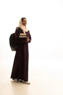 بورتريه من الجانب لطالبة جامعية عربية خليجية سعودية سمراء ترتدي العباءه والحجاب وحقيبة الظهر تحمل مجموعة من الكتب ، المناهج والمواد التعليمية الحديثة، التعليم العالي في جامعات المملكة،الاستعداد للعام الجامعي الجديد، خلفية بيضاء