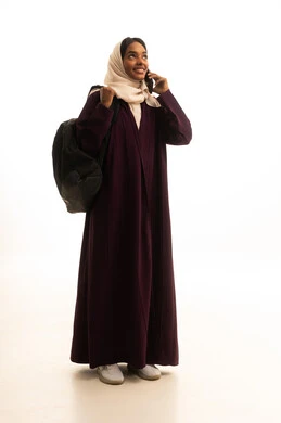 اجراء مكالمة هاتفية، برامج وتطبيقات التعليم والدراسة اونلاين ، دمج التقنيات الحديثة بالتعلم والتدريب، التعليم باستخدام التكنولوجيا، بورتريه لطالبة عربية خليجية سعودية ترتدي العباءة و الحجاب وحقيبة الظهر تمسك بيدها الهاتف المحمول، خلفية بيضاء