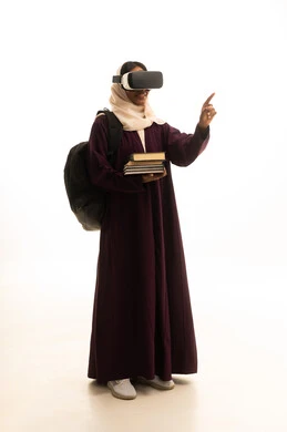 بورتريه لطالبة عربية خليجية سعودية ترتدي العباءة و الحجاب تضع نظارة الفي ار ثلاثية الأبعاد تحمل مجموعة من الكتب، محاكاة العالم الخيالي، دمج التقنيات الحديثة بالتعلم والتدريب، التعليم باستخدام تقنية العالم الافتراضي، خلفية بيضاء