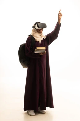 الاشارة باصبع السبابة الى شئ ما ، محاكاة العالم الخيالي، دمج التقنيات الحديثة بالتعلم والتدريب، التعليم باستخدام تقنية العالم الافتراضي، بورتريه لطالبة عربية خليجية سعودية ترتدي العباءة و الحجاب تضع نظارة الفي ار ثلاثية الأبعاد تحمل مجموعة من الكتب،  خلفية بيضاء