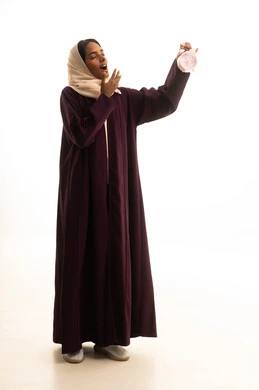 تعابير النعاس والحاجه الى النوم ، قدوم وقت الامتحانات والمذاكرات، تطوير المناهج والمواد التعليمية في السعودية، استغلال الوقت في الدراسة والمذاكرة, بورتريه لطالبة جامعية عربية خليجية سعودية ترتدي العباءة والحجاب وتحمل بيدها ساعة منبه , خلفية بيضاء.