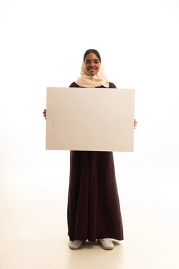 إعلان وعرض تسويقي، موك اب مربع أبيض، استخدام وسيلة توضيحية تعليمية، بورتريه لسيدة عربية خليجية سعودية ترتدي العباءة والحجاب تمسك بيدها لوحه بيضاء مربعه فارغة تنظر إلى الكاميرا بإيماءات السعادة ، خلفية بيضاء