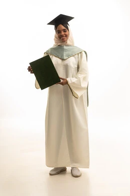 A portrait of a Gulf Arab Saudi female student wearing a graduation gown, cap, and graduation cloak, using a laptop with expressions of joy, embodying the concepts of excellence and success, distance learning using a laptop, celebrating the completion of her university stage, with a white background.