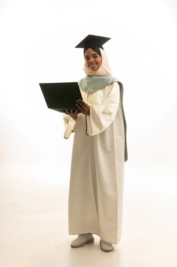 مفهوم التفوق والنجاح،  التعليم عن بعد باستخدام اللابتوب ، الاحتفال بإنهاء المرحلة الجامعية، بورتريه لطالبة عربيه خليجيه سعوديه ترتدي روب التخرج والقبعة وعباءة التخرج تستخدم جهاز الحاسوب المحمول بتعابير السرور، خلفية بيضاء