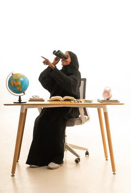 A portrait of a Gulf Arab Saudi student wearing an abaya and hijab and VR glasses sitting at a table in front of a globe model and books, simulating a fantasy world, setting a specific goal, the approach of exam time and studying, the concept of research and exploration around the world, with a white background.